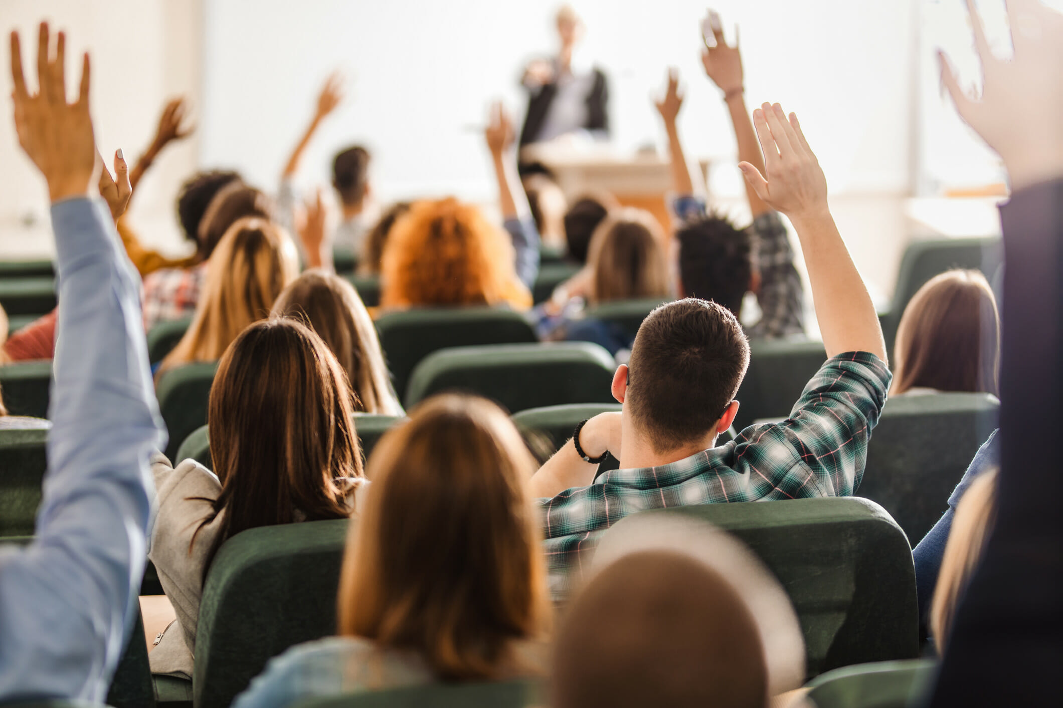 College students raising hands in class